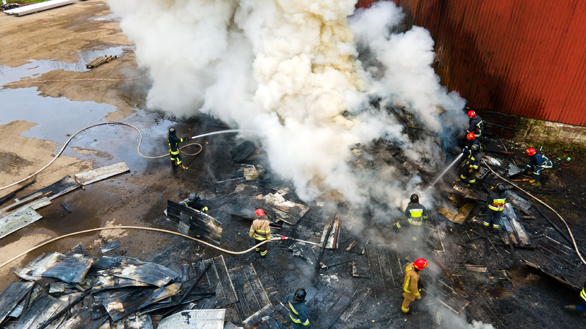 Bombeiros a atuar numa área afetada por incêndio e fumo intenso.
