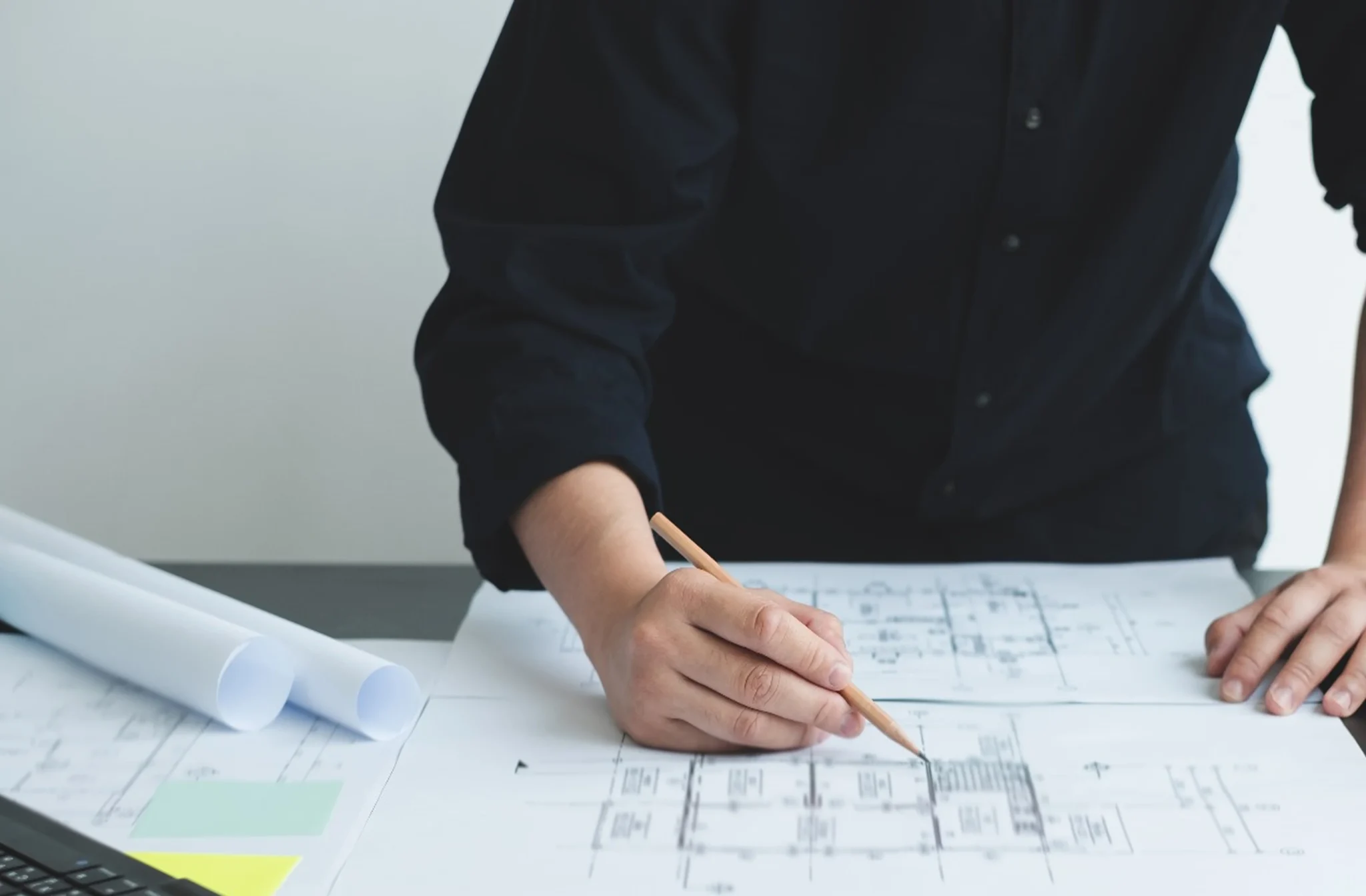Profissional a analisar um desenho técnico sobre uma mesa de trabalho.
