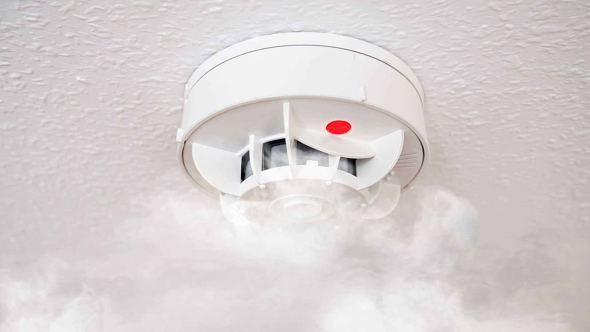 Detetor de fumo instalado no teto com presença de fumo.
