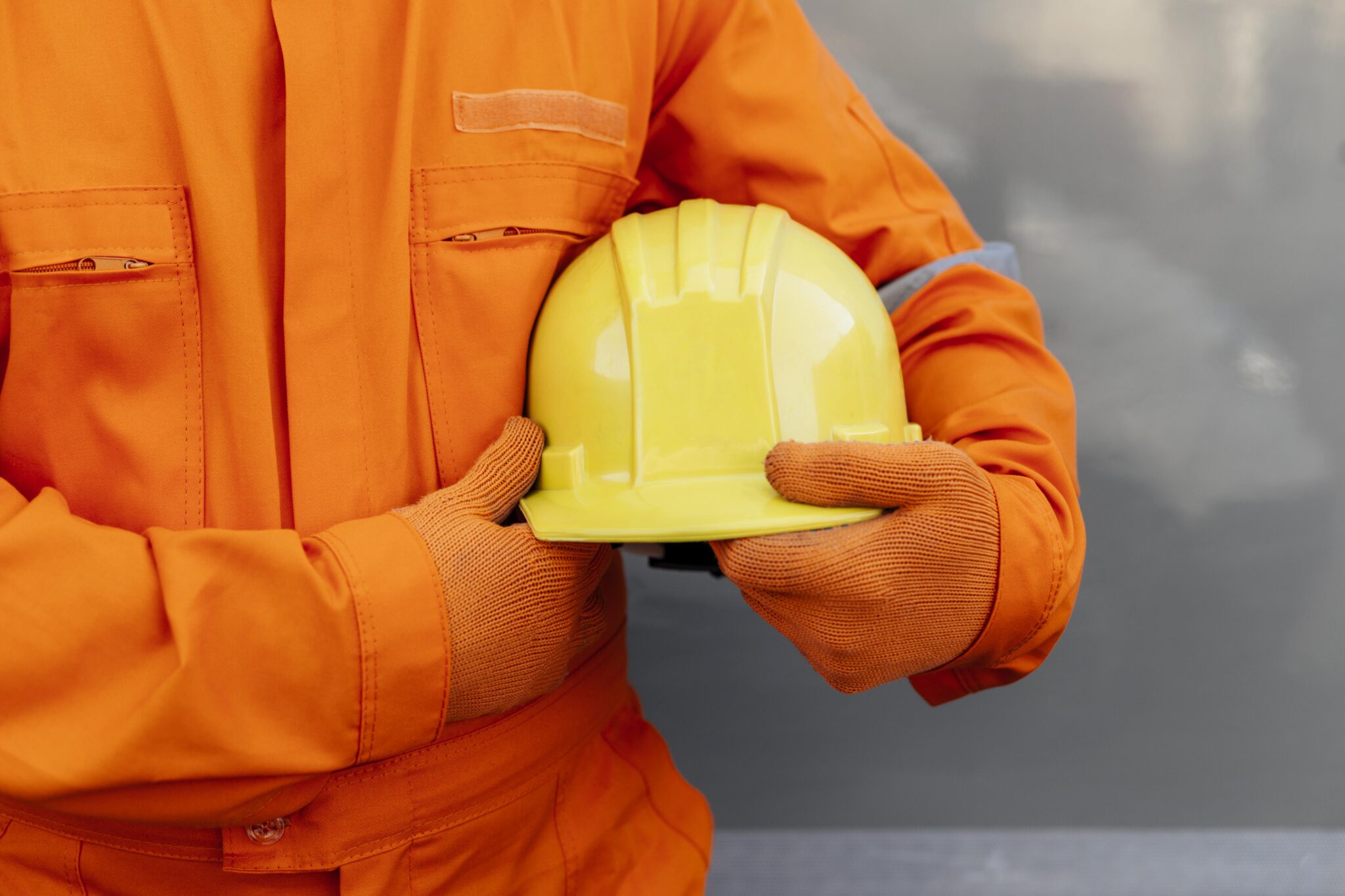 Profissional com vestuário de alta visibilidade a segurar um capacete de proteção.