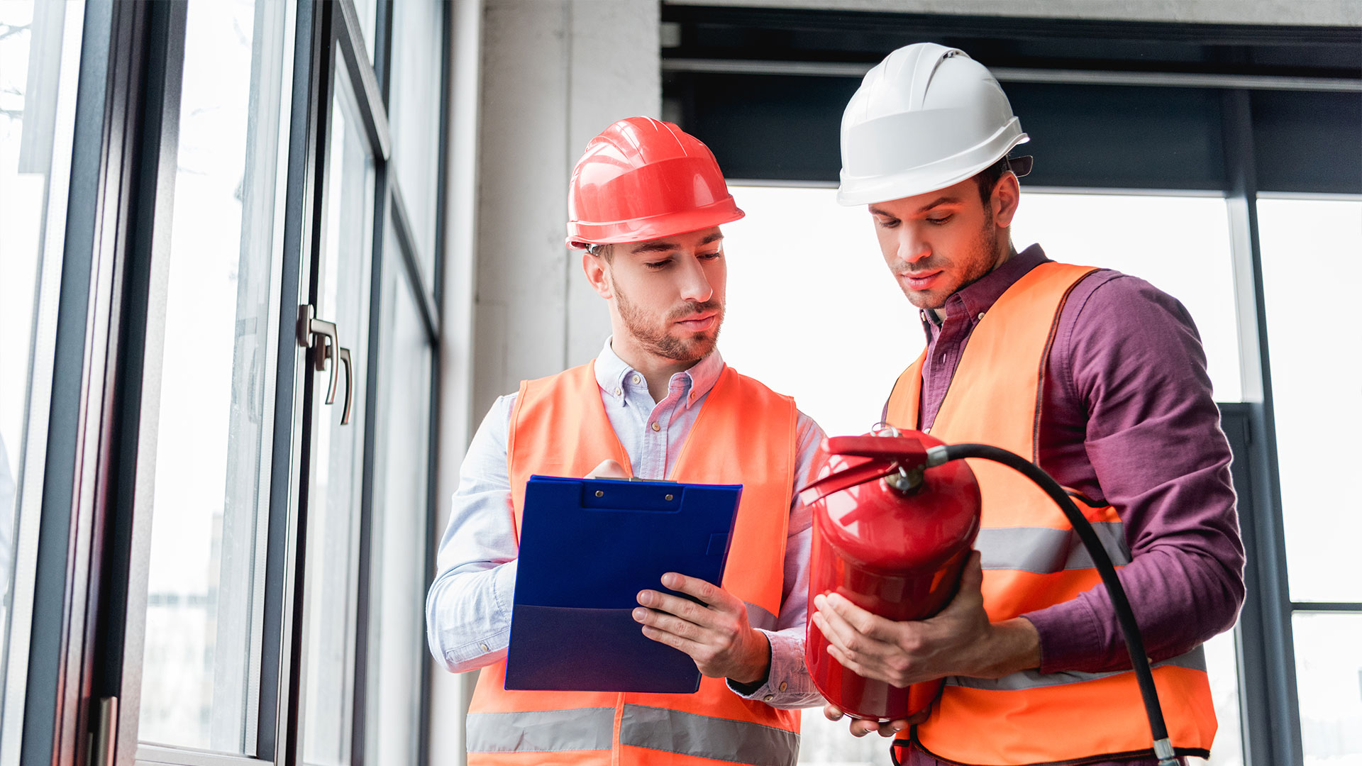 Técnicos equipados com capacete a analisar um extintor.