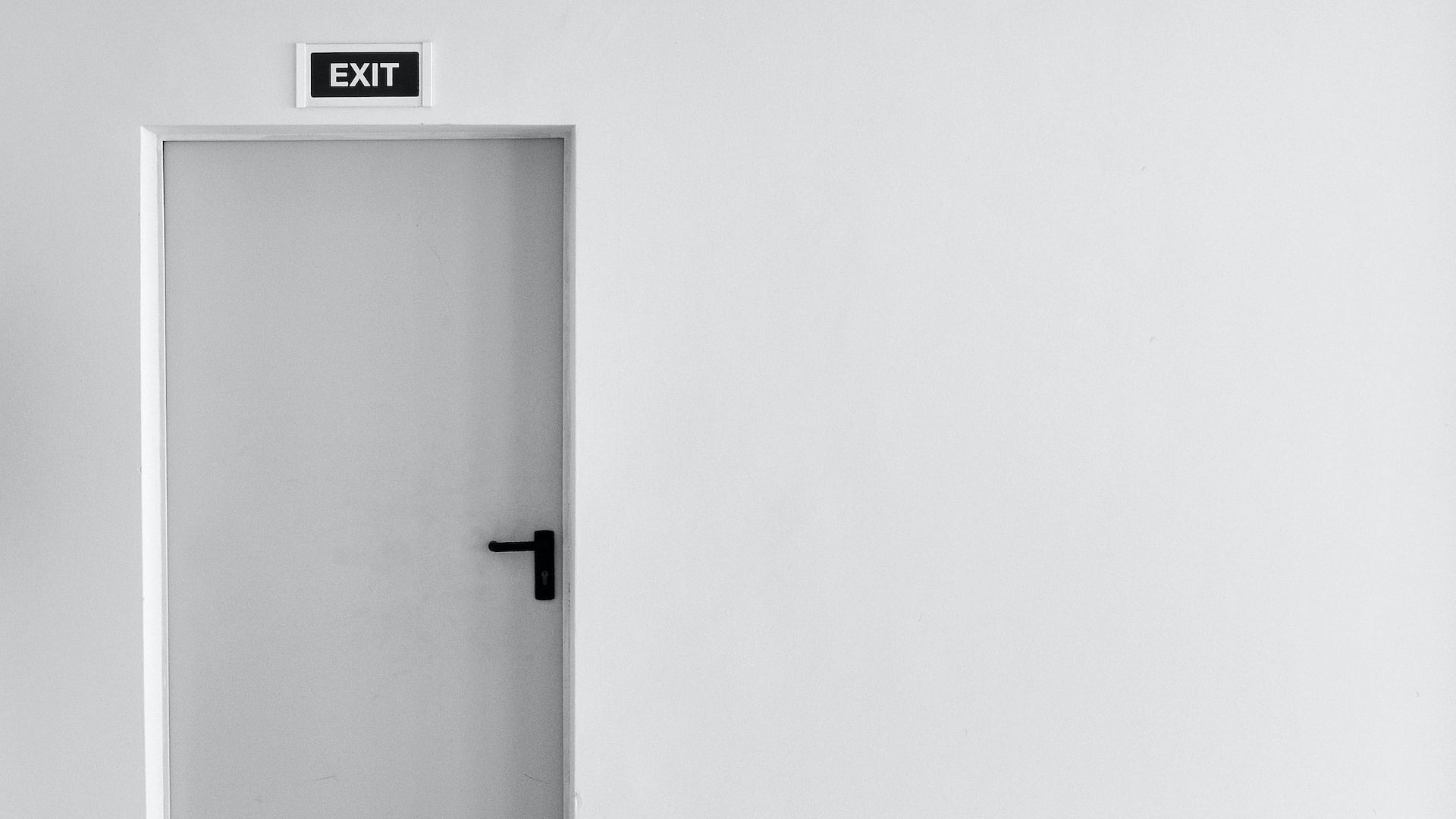 Porta interior branca identificada com sinal de saída.