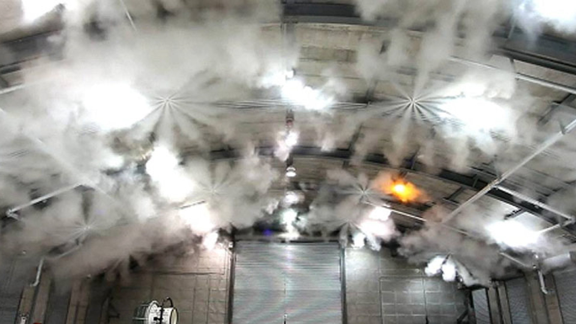 Sistema de extinção em funcionamento com descarga de agente numa instalação industrial.